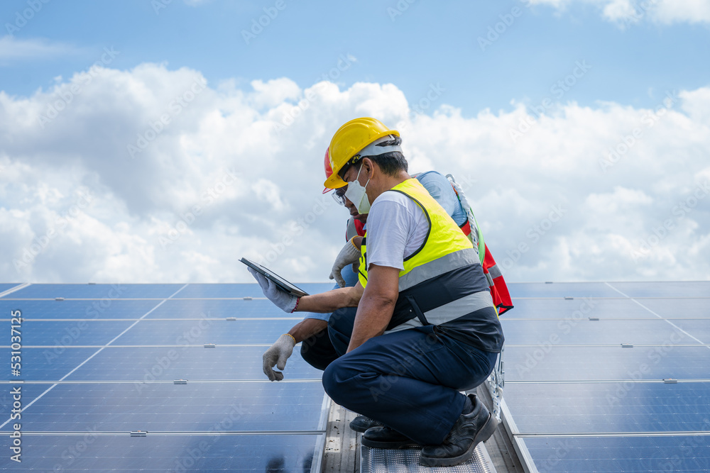 Poster technician wearing safety harness belt during installing the solar panels on roof structure of build