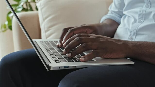 Hands of unrecognizable African American businessman typing fast on laptop keyboard. Work from home concept