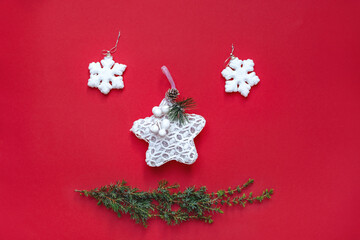 Merry Christmas smile. New Year's decorations lie like cheerful face on red background. White snowflake toys and green Christmas tree branch. Happy holidays. Card with Copy Space for text.