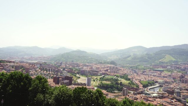 Top panoramic view of Bilbao city. Perspective from above of the city. In front the old town and the river Nervion, in background the mountains that surrounding the city. Foggy day. Static video