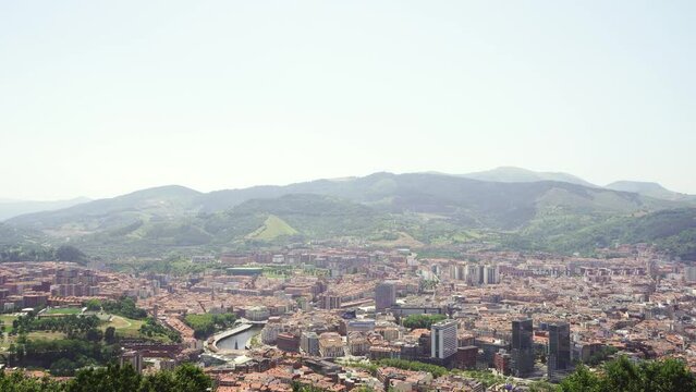 Top panoramic view of Bilbao city. Perspective from above of the city. In front the old town and the river Nervion, in background the mountains that surrounding the city. Foggy day. Static video