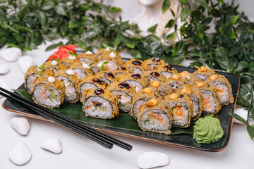 Served warm sushi with ginger and wasabi on a black stone plate.