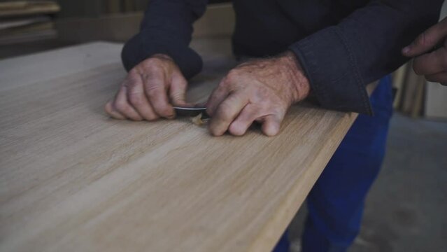 a carpenter apprentice raking wood with a scraper