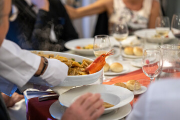 Cerimonia, servire a tavola, cameriere che serve pietanza a base di pesce tra commensali
