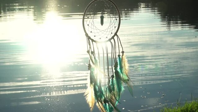 Morning breeze blows the dream catcher with a crimson stream in the background