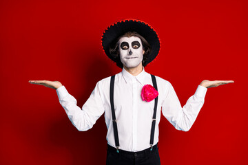 Photo of zombie undead role play funny guy death day facial print makeup hold open arms presenting two products selection wear hat costume suspenders shirt isolated red color background