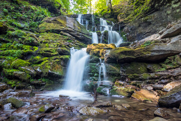Fototapeta premium Amazing sunny summer landscape with beautiful Shypit waterfall in Carpathian mountains, Multi-stage waterfall in the forest in the mountains.Nature travel background suitable for wallpaper or cover