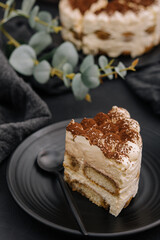 Traditional italian tiramisu cake on black plate