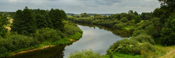 widescreen panoramic view of the neman river with banks overgrown with greenery on a summer day