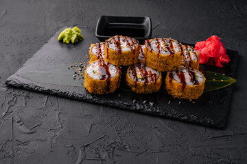 Warm sushi with ginger and wasabi served on a black stone plate