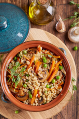 Pearl barley grain porridge with carrot, mushrooms, green peas and onion. Lenten vegetarian dish.