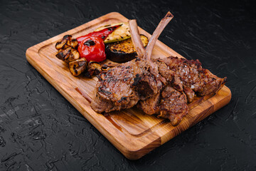 Tasty grilled lamb ribs with vegetables on board