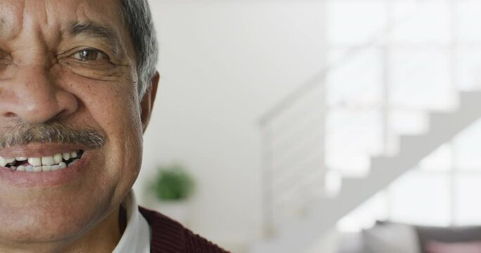 Video close up portrait of senior biracial man in living room smiling to camera, with copy space