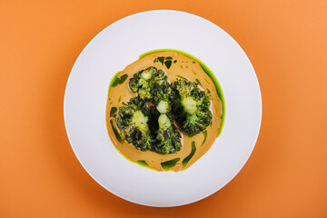 Pumpkin cream soup with broccoli on plate
