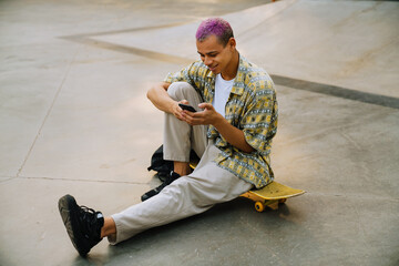 Young handsome stylish short-haired smiling boy sitting on skateboard © Drobot Dean