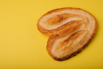 Butterfly puff pastry or palmier cookie on yellow background