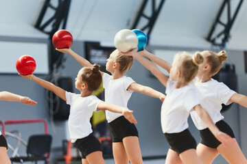 Group of kids, little girls, beginner gymnastics athletes in sports uniform at training at sports...