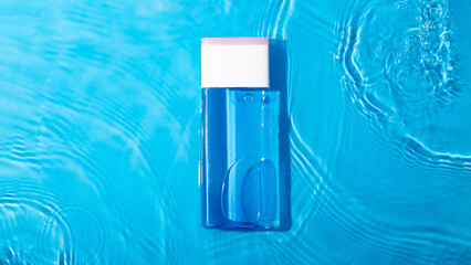 Mock up blue miccelar water, moisturizing in water on blue background. Template for design Blank label for branding mock-up. Summer water pool fresh concept. Flat lay, top view..