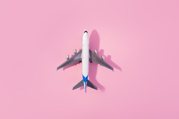 Top view of white model plane, airplane toy on isolated pink background. Flat lay with copy space. Trip or travel banner..