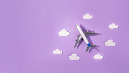 Flat lay design of travel concept with plane and cloud on purple and  copy space. Small airplane model toy for children.