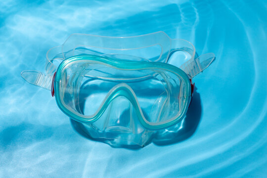 flat lay shot of blue diving mask over turquoise blue background. minimalist photo of dive mask under water.