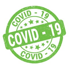 COVID - 19 text written on green round stamp sign.