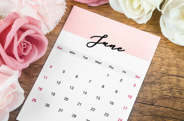 The June 2023 Monthly calendar for 2023 year with pink rose on wooden background. - Powered by Adobe