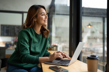 Asian woman working with laptop in coffee shop, business financial concept.