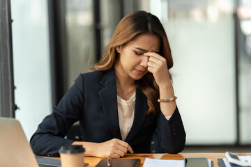 Tired asian business woman with headache at office, feeling sick at work. office syndrome concept.