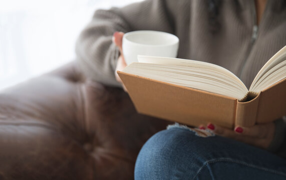 Young girl drinking tea and reading a book