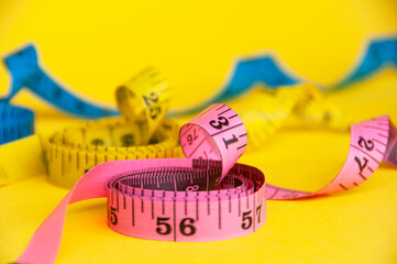 Red, yellow and blue measuring tapes on yellow cover background. Copy space and weight loss concept