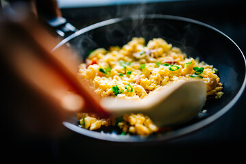 Woman cooking tasty scrambled eggs in frying pan 