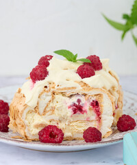 Baked meringue roll with cream and fresh red raspberry, white background.
