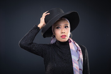 Portrait of a beautiful female model wearing hijab, a lifestyle apparel for Muslim women isolated on grey background. Idul Fitri and hijab fashion concept.