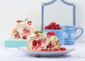 Baked meringue roll with cream and fresh red raspberry, white background.