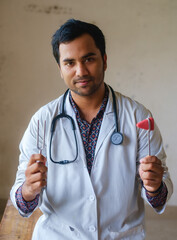 South asian doctor with a medical hammer and tuning fork in hand. Bangladeshi medical student with...