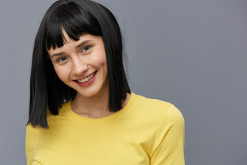 a happy, joyful woman stands on a gray background and smiles broadly looking into the camera with beautiful, even teeth