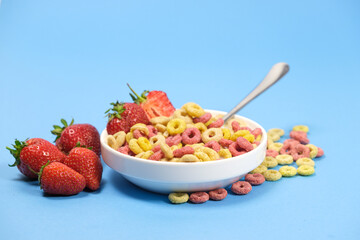 Quick breakfast cereal - rings with milk and strawberries on a blue background.