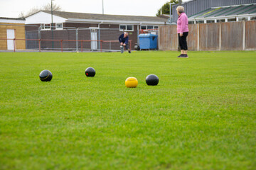 Male bowls towards the yellow Jack in a competition game of Crown green bowling , whilst the female...