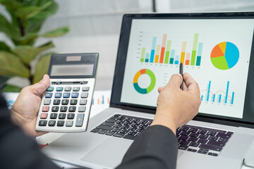 Asian accountant working and analyzing financial reports project accounting with chart graph and calculator in modern office, finance and business concept.