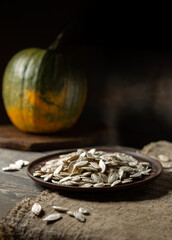 Pumpkin seeds on a brown plate on a wooden background.