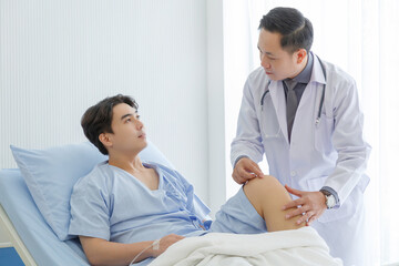 Fototapeta premium Senior doctor and young male patient who lie on the bed while checking symptom, consult and explain in hospital wards.