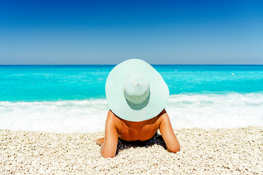 Carefree woman with straw hat sunbathing lying on a idyllic beach, Kefalonia, Ionian Islands, Greek Islands, Greece