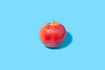 Big ripe red apple on a blue background - juicy summer fruit
