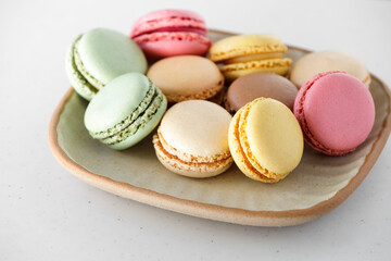 Various colorful macaroons on a plate on a white table,