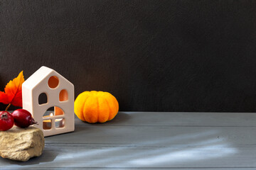 Halloween. On a black and gray background are a house, pumpkin and small apples on a stone