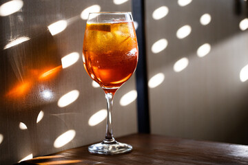 Glass of Aperol spritz cocktail with orange photography taken with sun light