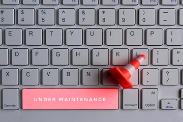 Computer system under construction, maintenance, repair concept. Safety cone and keyboard computer
