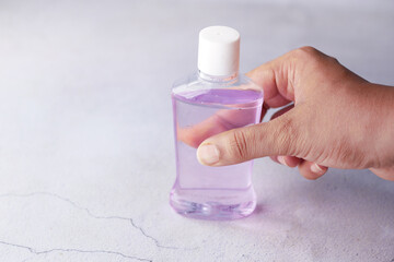  hand hold a mouthwash liquid container 