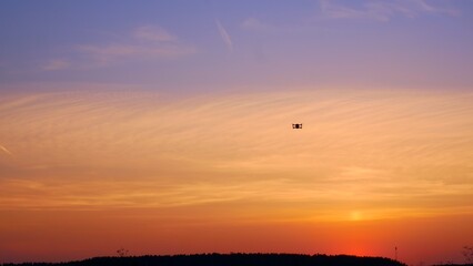 A drone flies in the sunset sky and glows with its light bulbs. A futuristic future where drones...